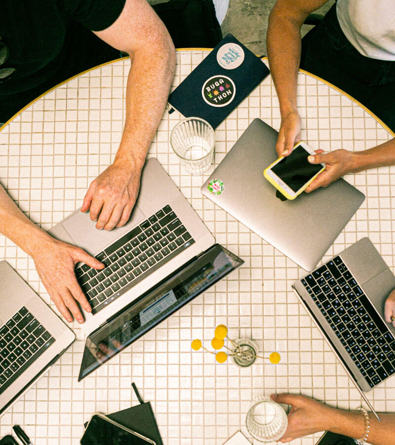 An image of people working online with laptops and phone that is the featured image of business support solutions at Not Fade Away.